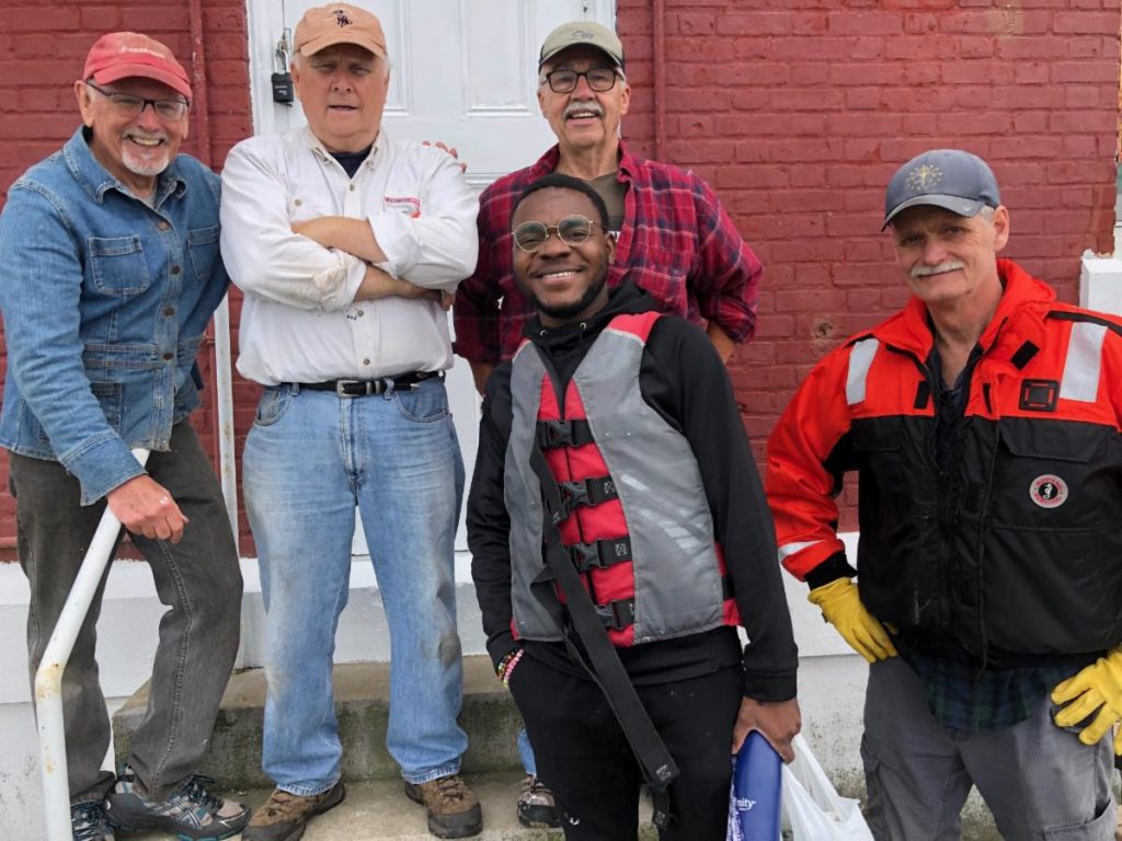  In June a crew went out to scrape, paint and clean Ledge Lighthouse in advance of summer tours. Ledge Light Foundation president Bruce Buckley (peach cap) and long-time volunteer Phil Medbury (grey cap) ran the show, with recruits Martin Bobenski (red cap), Rock Charles (cap free), and Al Doucette (tan). NLMS.